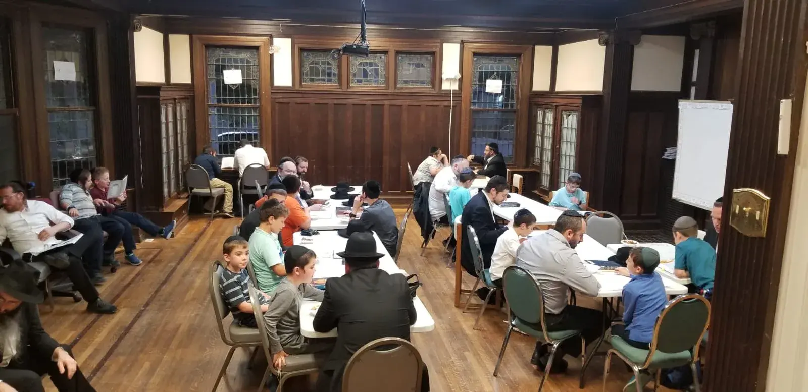 Students learning at long tables in a wood-panelled study hall with leaded windows