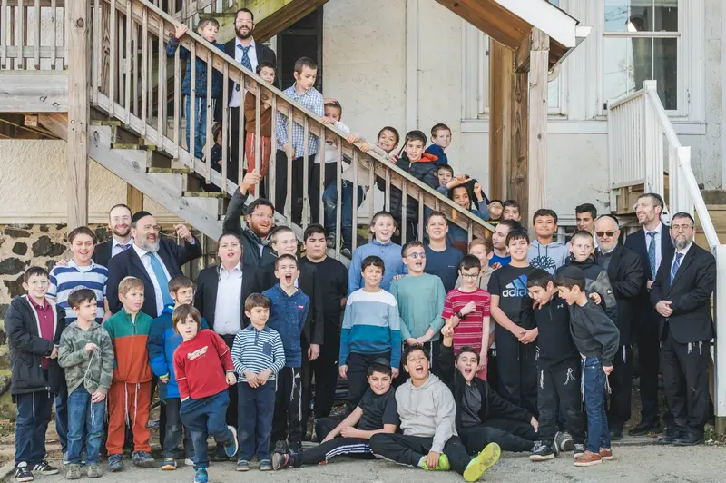 Tashbar students and staff gathered on the wooden stairs outside the school building