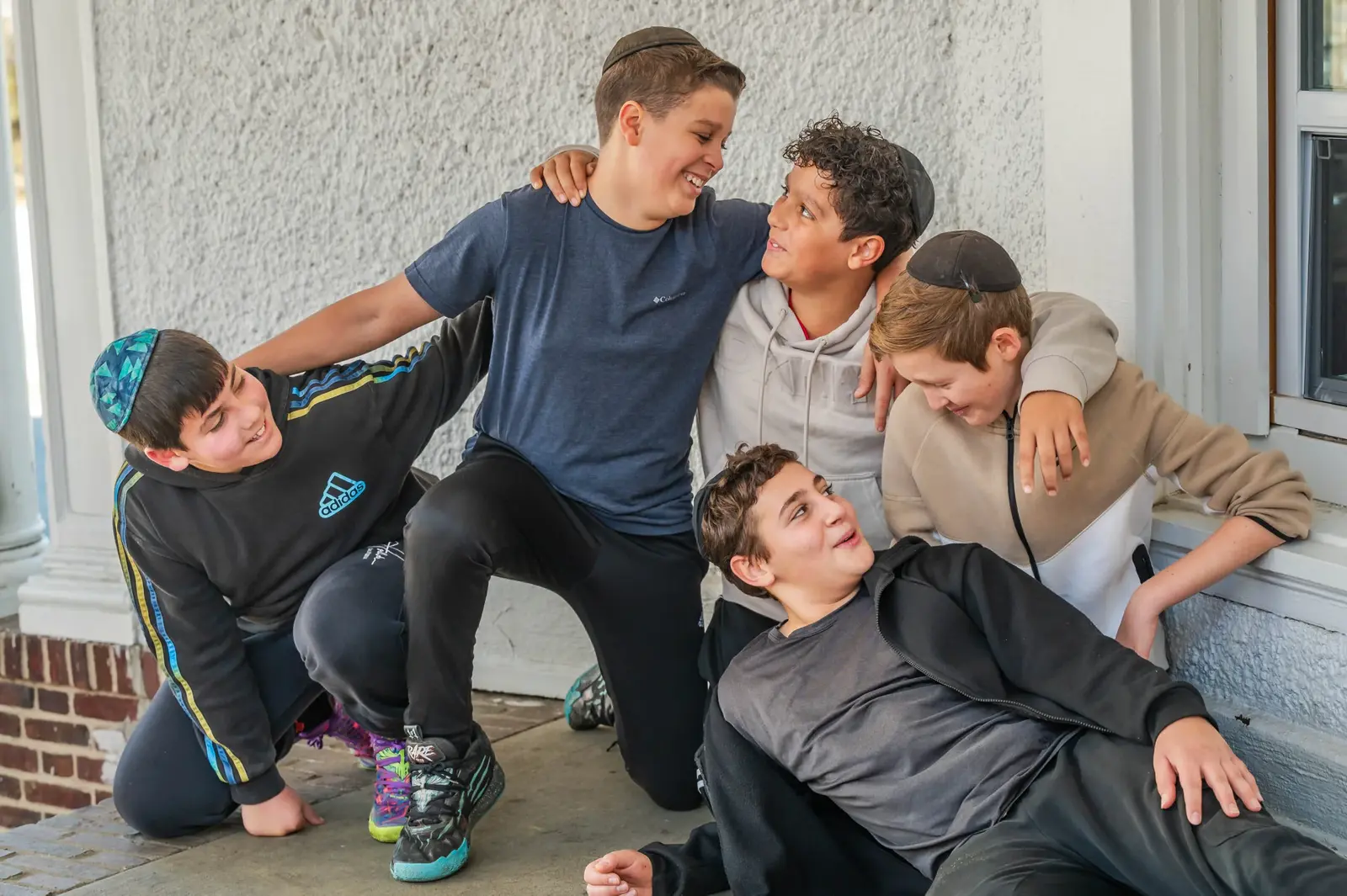 Five Tashbar boys laughing together on the school's front steps